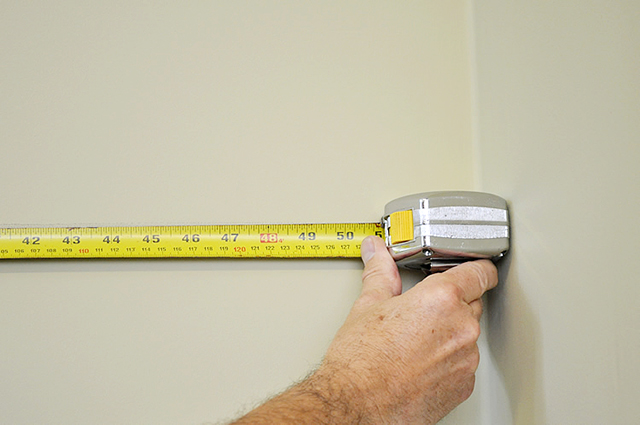 Измерение ширины стены рулеткой